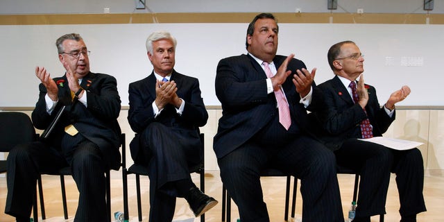 In this July, 24, 2012, file photo, from left, John Sheridan, president and CEO of The Cooper Health System, applauds with George Norcross III, New Jersey Gov. Chris Christie and Dr. Paul Katz during an event in Camden, N.J.