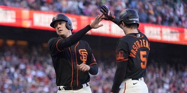 The San Francisco Giants' Wilmer Flores, left, is congratulated by Mike Yastrzemski after scoring against the Milwaukee Brewers during the eighth inning in San Francisco Saturday, July 16, 2022. 