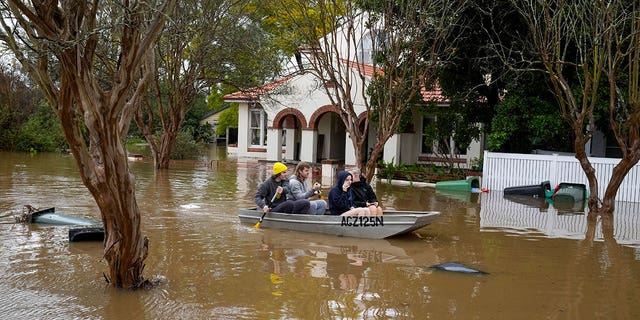 People paddle through a flooded street at Windsor on the outskirts of Sydney, Australia, Tuesday, July 5, 2022. Hundreds of homes have been inundated in and around Australia’s largest city in a flood emergency that was impacting 50,000 people, officials said Tuesday.