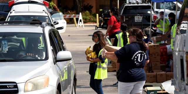 Volunteers provide bananas and other food items to the needy at a food distribution event in June 2022 sponsored by the Second Harvest Food Bank of Central Florida and Orange County at St. John Vianney Church in Orlando, Florida. High food and gas prices are squeezing working families, sending some to food pantries for the first time.