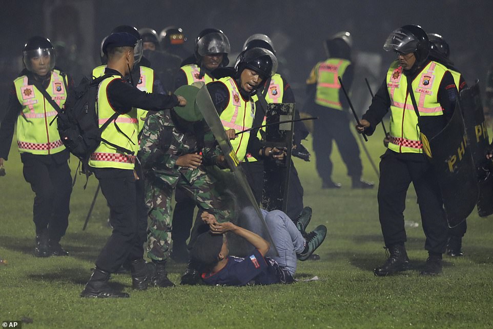Security officers detain a fan during a clash between supporters of two Indonesian soccer teams at Kanjuruhan Stadium in Malang