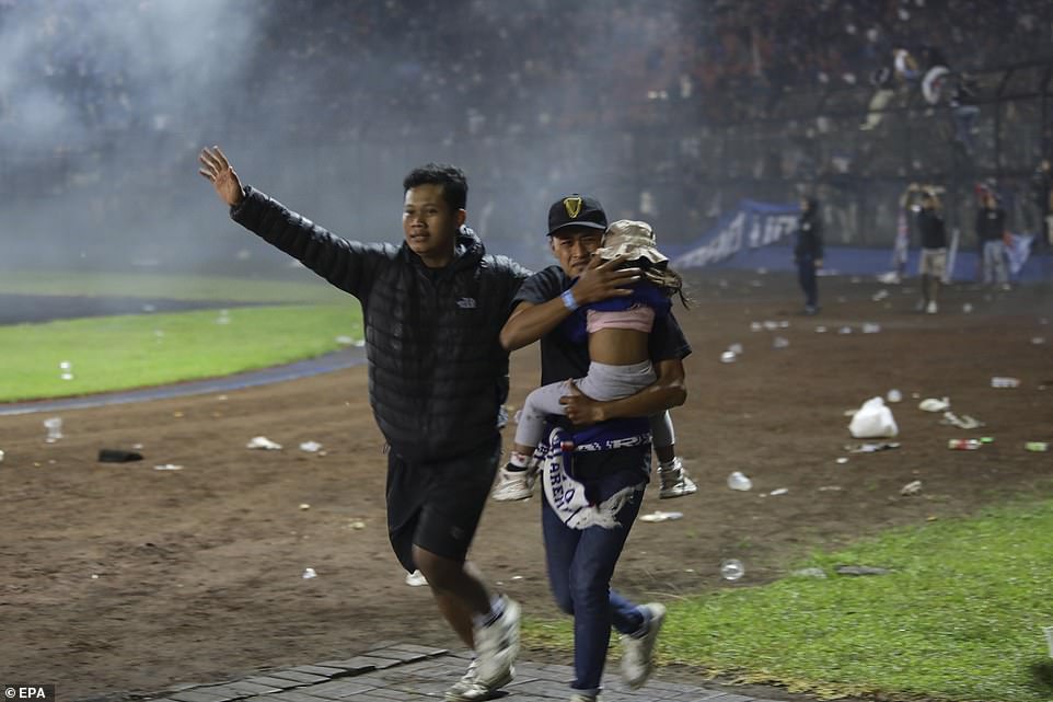 Football fans help a young girl escape from the Kanjuruhan Stadium in Malang, East Java, after riots broke out following the match