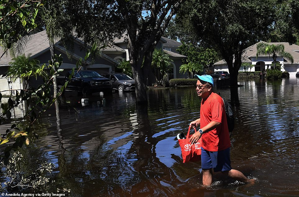 Edgar Soriano wades through water in his neighborhood after picking up items from his home which was flooded by rain from Hurricane Ian