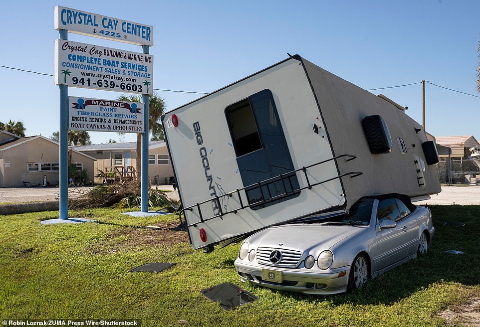 A wind blown camper-trailer rests on a passenger car along a highway in Punta Gorda, Florida
