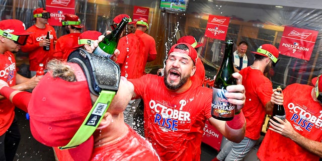 Kyle Schwarber, #12 of the Philadelphia Phillies, celebrates with teammates in the locker room after clinching the Wild Card, their first playoff berth since 2011 with a 3-0 win over the Houston Astros at Minute Maid Park on Oct. 3, 2022 in Houston.