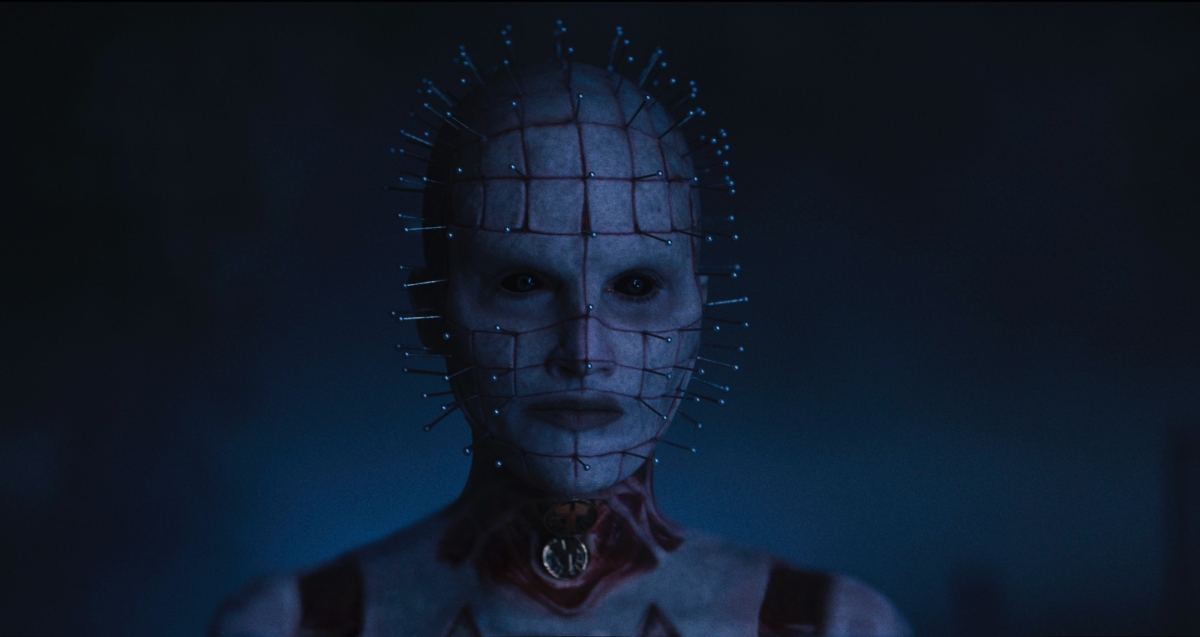 'Hellraiser' Pinhead/The Priest (Jamie Clayton). She has black eyes and pins stabbed all over her head looking straight ahead.