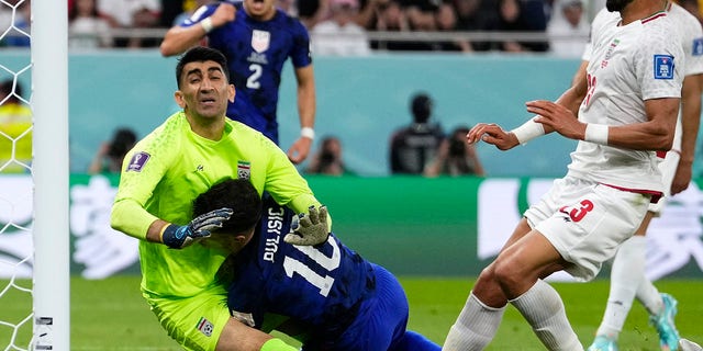 Christian Pulisic of the United States, center, collides with Iran's goalkeeper, Alireza Beiranvand, left, while scoring a goal during the World Cup Group B match at Al Thumama Stadium in Doha, Qatar, on Nov. 29, 2022.