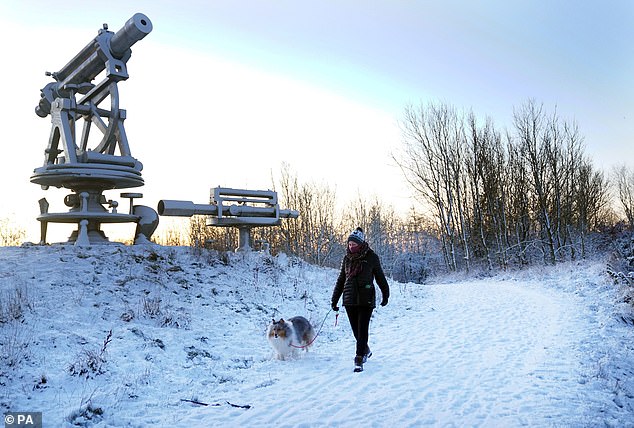 A woman walks her dog through overnight snow near the Terris Novalis sculpture in Consett, County Durham