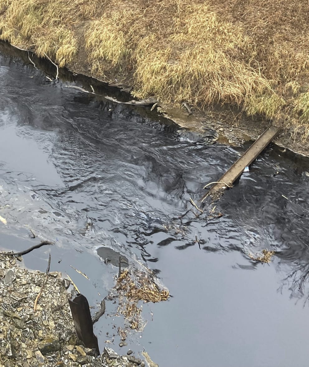 The river water is stained black with oil and polluted