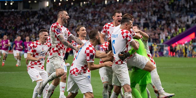 Croatia players celebrate with goalkeeper Dominik Livaković after he saved three penalties in the shootout against Japan during the World Cup match at Al Janoub Stadium on Dec. 5, 2022, in Al Wakrah, Qatar.