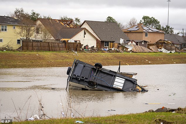 A camping trailer sits in a retention pond where a tornado was reported to pass along Mickey Gilley Blvd., near Fairmont Parkway