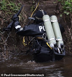 A police diver prepares to climb back up the river bank