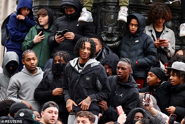 Digga D (pictured centre) invited his fan base to join him in Piccadilly Circus in London earlier this afternoon where he filmed a new music video