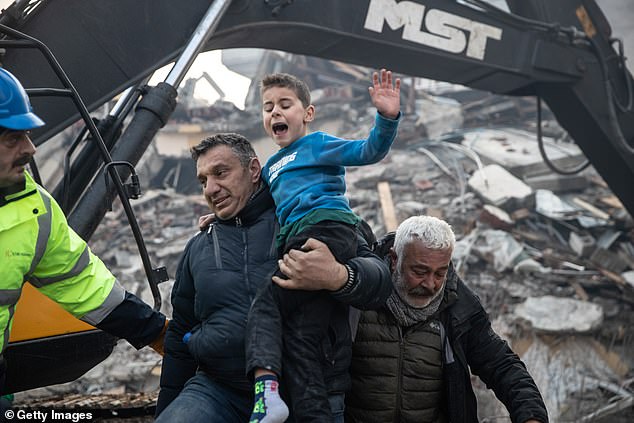 Pictured: Rescue workers carry Yigit Cakmak, an 8-year-old survivor at the site of a collapsed building in Hatay, Turkey. He was saved 52 hours after the earthquake struck on Monday
