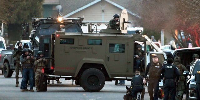 Law enforcement officers aim their weapons at a home during a standoff in Grants Pass, Ore., on Tuesday, Jan. 31, 2023. 