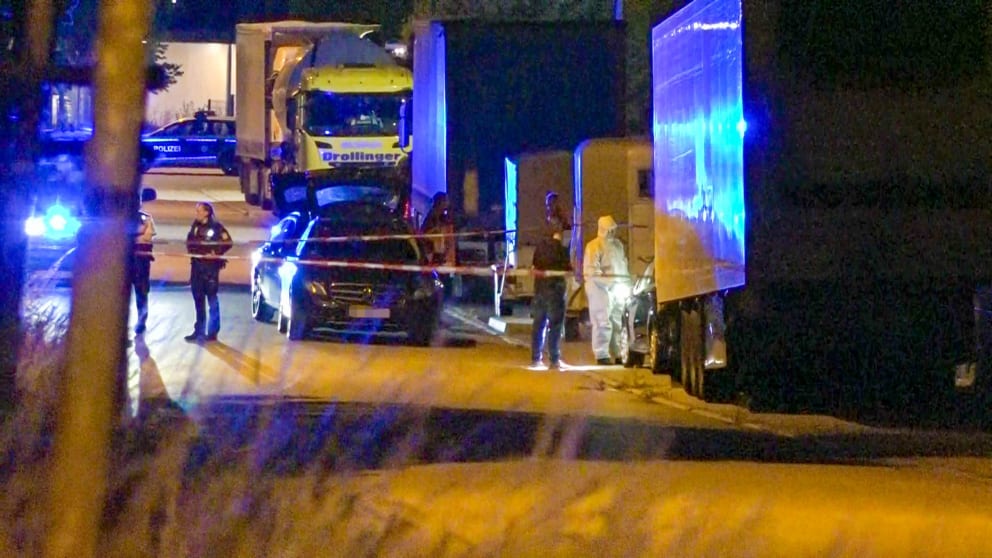 Police officers examine the car parked between trucks and horse trailers with the woman's body in it