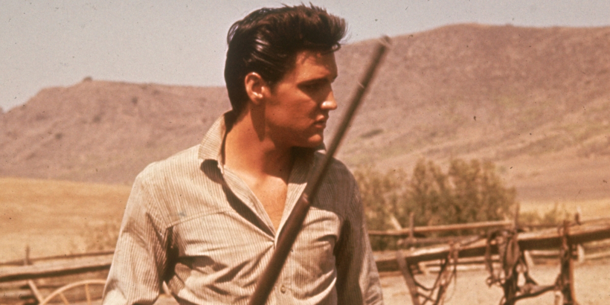 Elvis Presley on the set of his film 'Flaming Star' holding a rifle; Elvis practiced shooting at home a favorite hobby at Graceland.