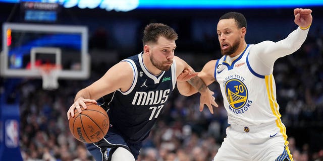 Luka Doncic, #77 of the Dallas Mavericks, dribbles the ball against Stephen Curry, #30 of the Golden State Warriors, on March 22, 2023, at the American Airlines Center in Dallas, Texas. 