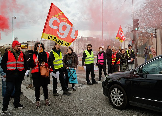 People wave General Confederation of Labour unions (CGT) flags as they block the traffic on Paris' peripheral boulevard