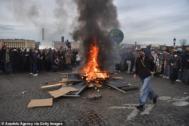 Protesters set fire to items as clashes take place with riot police during a demonstration