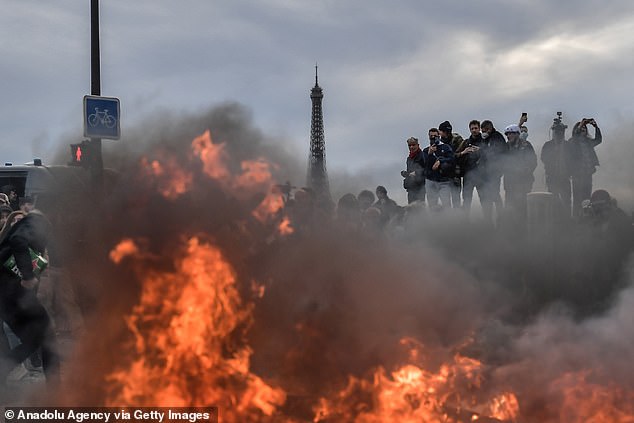 The Eiffel Tower is seen while protesters set fire as clashes take place with riot police during a demonstration against French government's plan to raise the legal retirement age