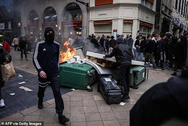 A demonstrator moves a mattress next to burning household waste containers during a demonstration in Bordeaux, southwestern France, on March 18, 2023