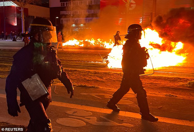 French CRS riot police secure the area near garbage cans on fire during a demonstration to protest the use by French government of the article 49.3, a special clause in the French Constitution, to push the pensions reform bill through the National Assembly without a vote by lawmakers, in Paris on March 18, 2023