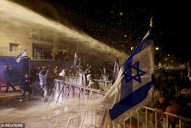 Protesters duck as they are hit by fierce jets from a water cannon in Jerusalem