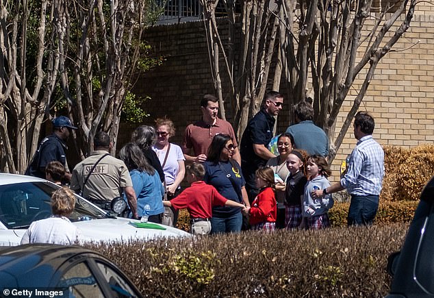 Children and adults wait outside The Covenant School in Nashville following the shooting