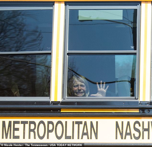 A terrified child presses her hand against the glass of a school bus window after being evacuated from The Covenant School