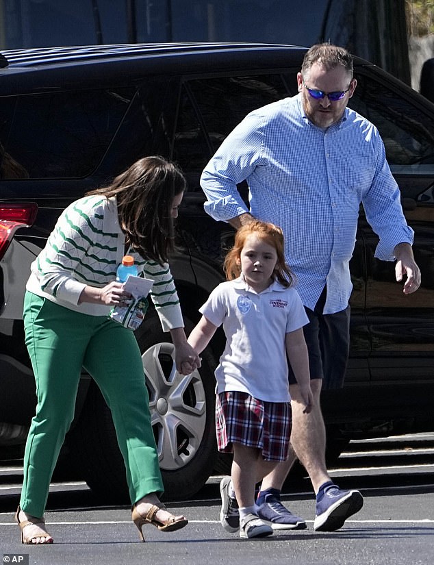Adults walk with a child at a reunification center at the Woodmont Baptist Church