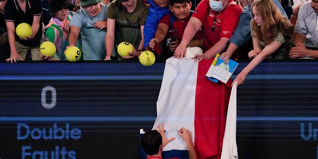 Daniil Medvedev of Russia autographs a Russian flag after defeating Marcos Giron of the U.S. in their first-round match at the Australian Open tennis championship in Melbourne, Australia, Monday, Jan. 16, 2023. 