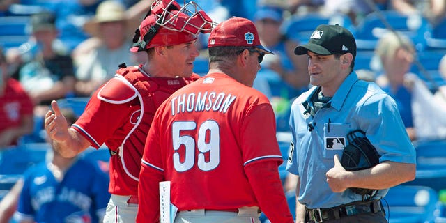Philadelphia Phillies catcher J.T. Realmuto and manager Rob Thomson argue with umpire Randy Rosenberg after Realmuto was ejected from a spring training baseball game in Dunedin, Fla., Monday, March 27, 2023.