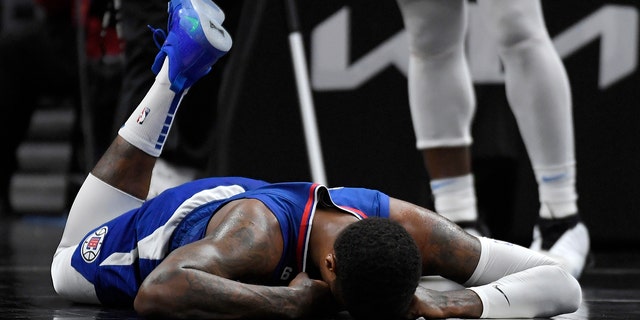 Paul George #13 of the Los Angeles Clippers lies on the floor after injuring his right knee on a foul by Luguentz Dort of the Oklahoma City Thunder in the second half at Crypto.com Arena on March 21, 2023 in Los Angeles, California.