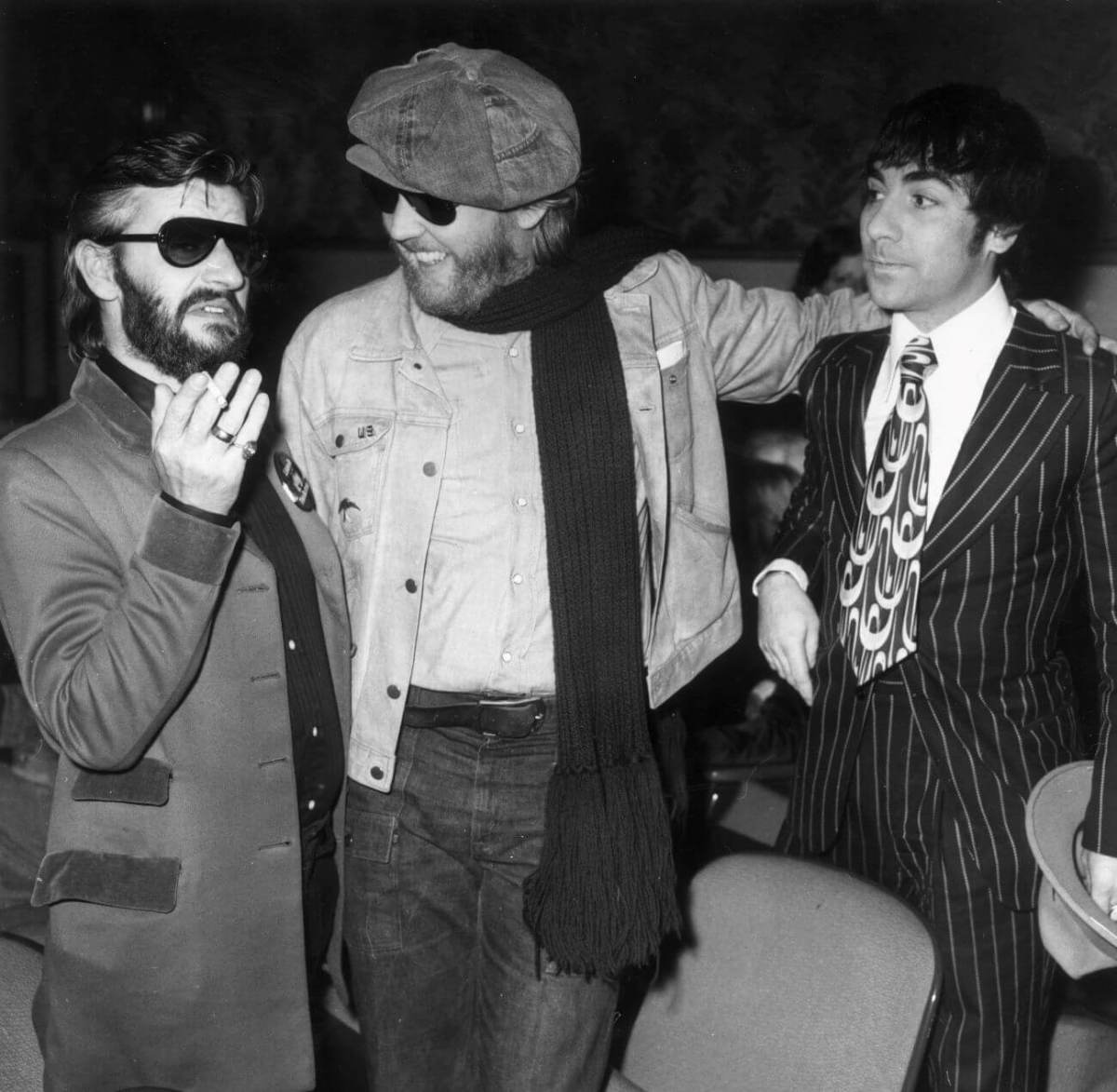 A black and white picture of Harry Nilsson standing with his arms around Ringo Starr and Keith Moon.
