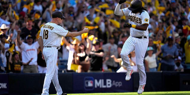 Josh Bell #24 of the San Diego Padres celebrate with third base coach Matt Williams #18 as he rounds the bases after hitting a home run in the second inning of Game 2 of the NLCS between the Philadelphia Phillies and the San Diego Padres at Petco Park on October 19, 2022 in San Diego, California.