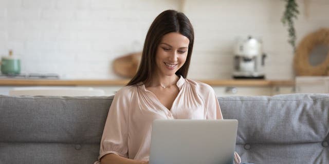 Woman smiles as she works on her laptop computer
