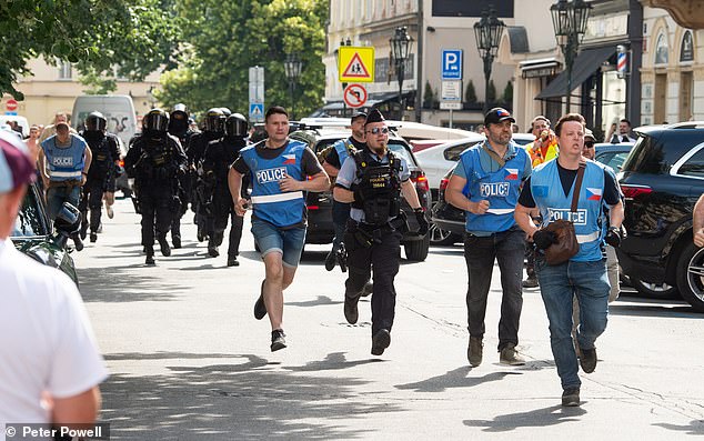 Pictured: Riot police and other officers are seen running down the streets of Prague yesterday
