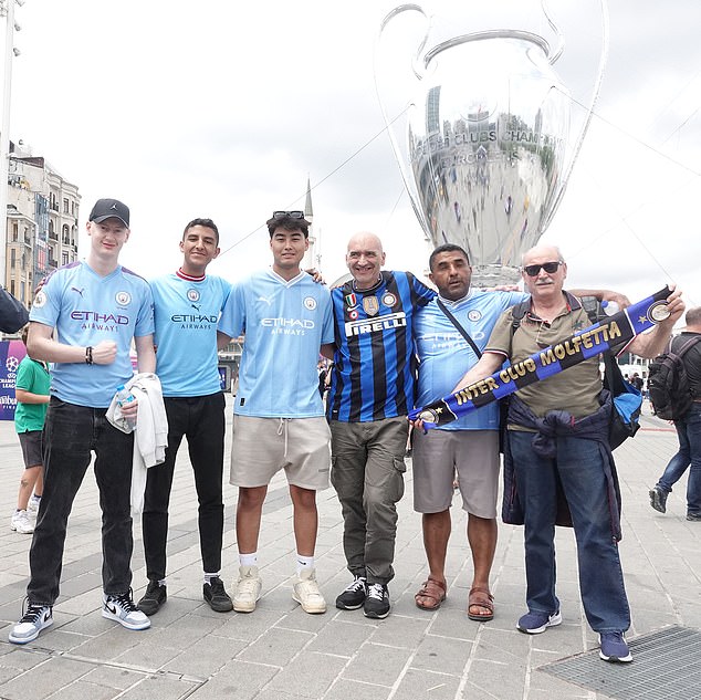Fans of both sides in the showpiece final pose for a photo in front of a monument of the trophy