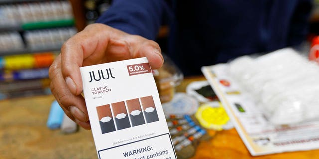 In this June 17, 2019, file photo, a cashier displays a packet of tobacco-flavored Juul pods at a store in San Francisco. 