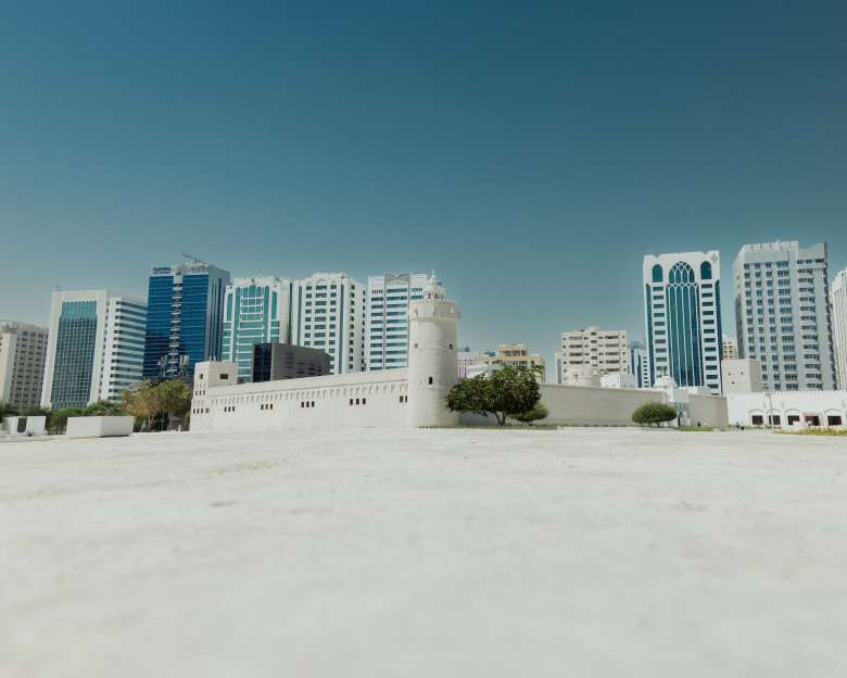 White sand beach in the foreground with Abu Dhabi skyscrapers in the background.