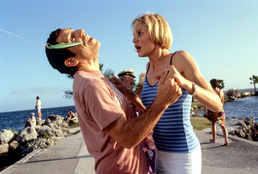 Ben Stiller with a fish hook pulling his head back while Cameron Diaz looks on in ‘There’s Something About Mary'