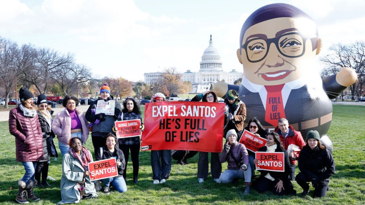 A group of protesters with a giant balloon depicting Congressman George Santos stand for a photograph outside the U.S. Capitol building