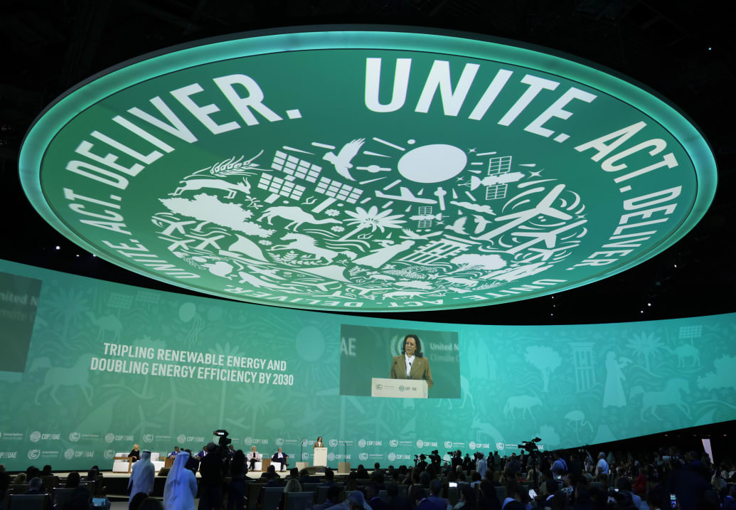A wide view of the audience at COP28. Kamala Harris is displayed on a screen.