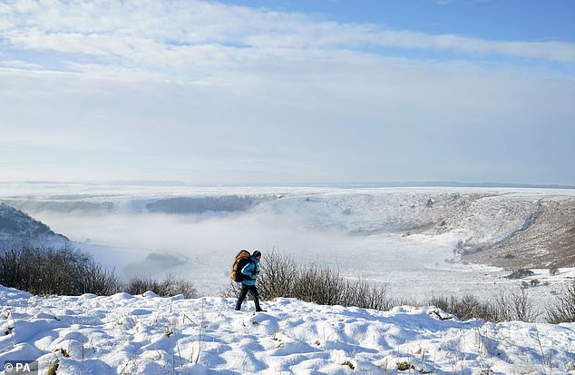 A person walks through snow above the Hole of Horcum at the North York Moors National Park, as scattered weather warnings for snow and ice are in place across the UK