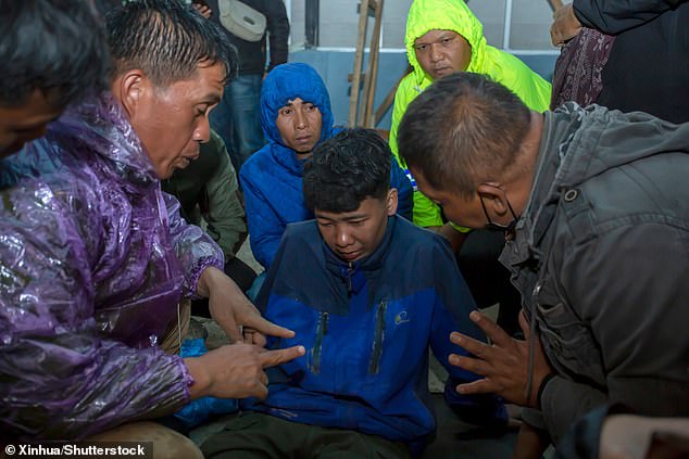 Rescuers talk to a man affected by Monday's volcano eruption in Marapi, Indonesia